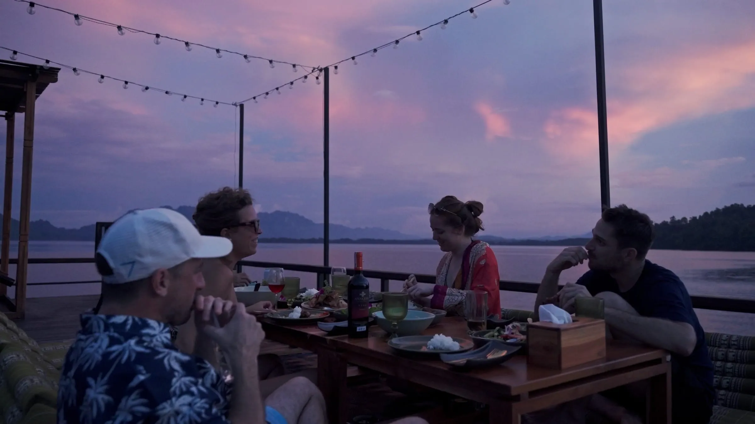 Dinner laid out under string lights on the deck as the sky turns pink.