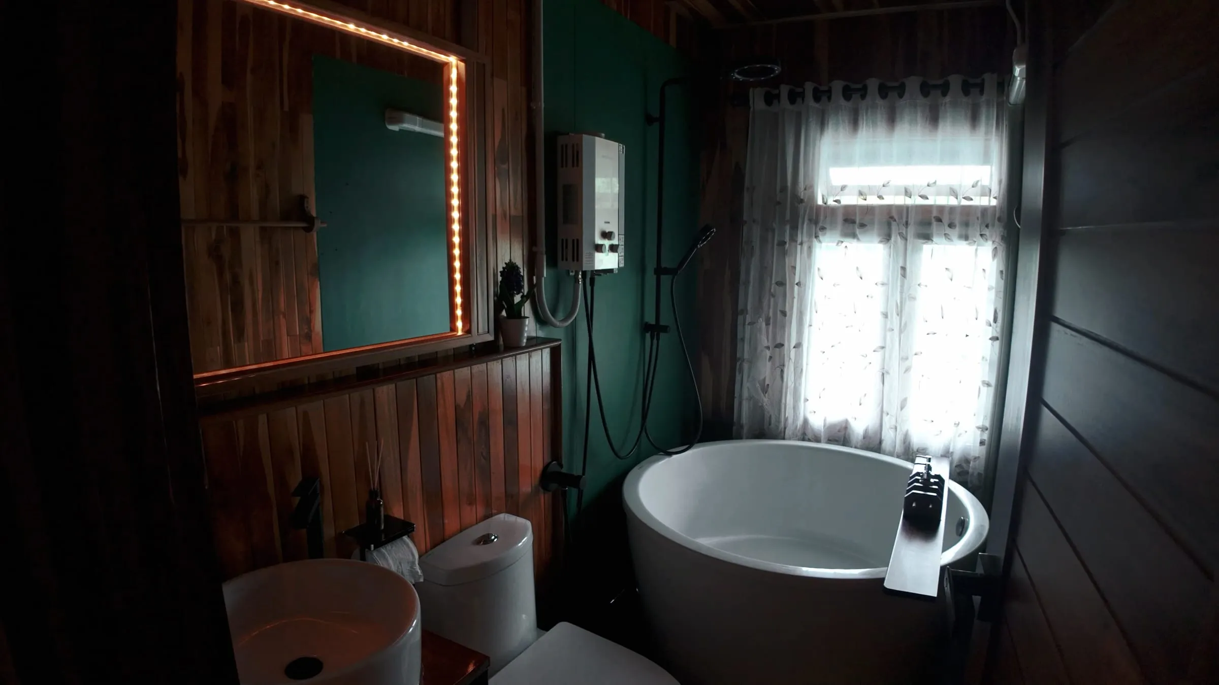 A private bathroom with a freestanding tub and wooden walls inside the floating house.