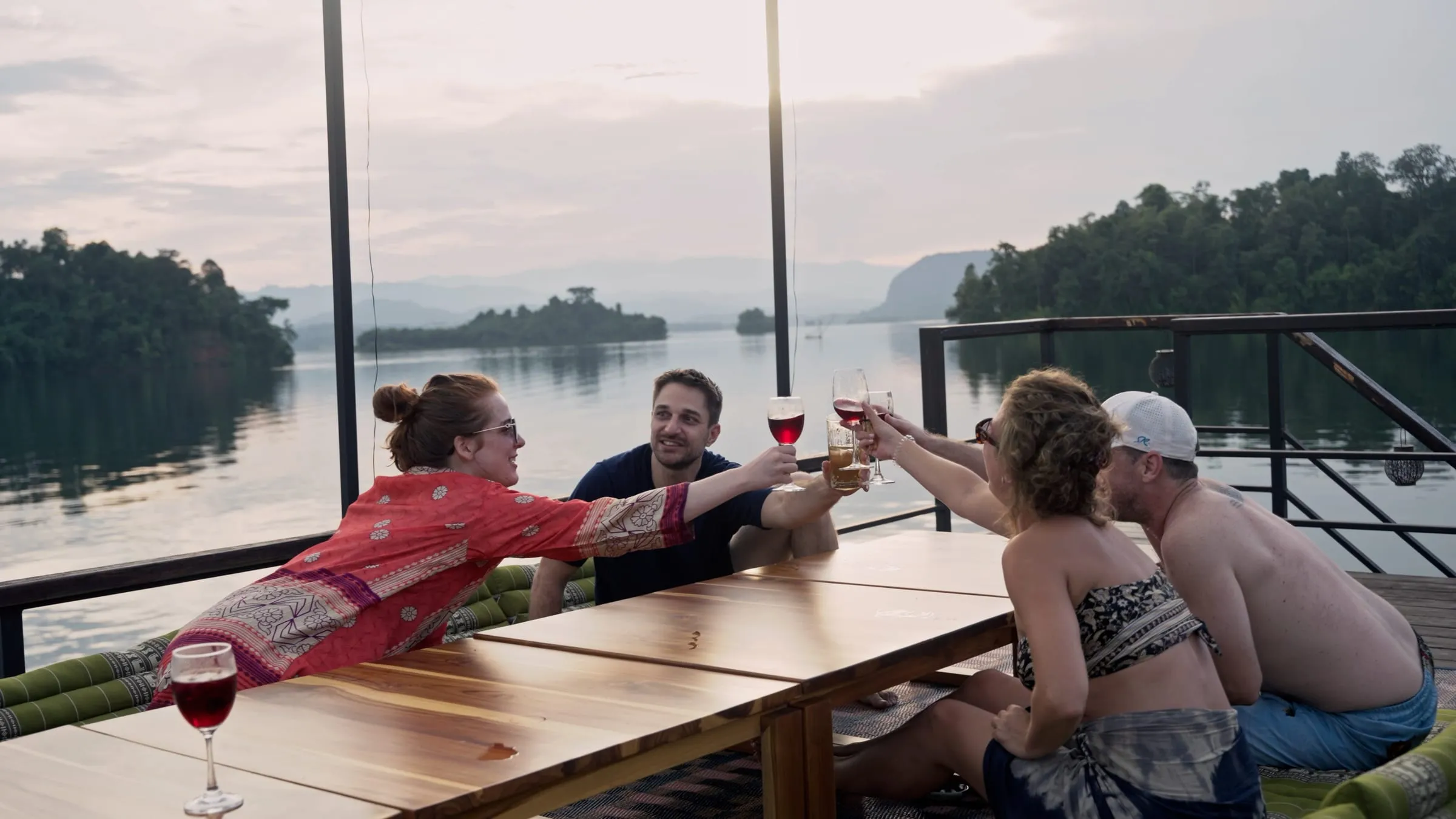 Travellers raising a toast around the long dinner table on the deck at sunset.