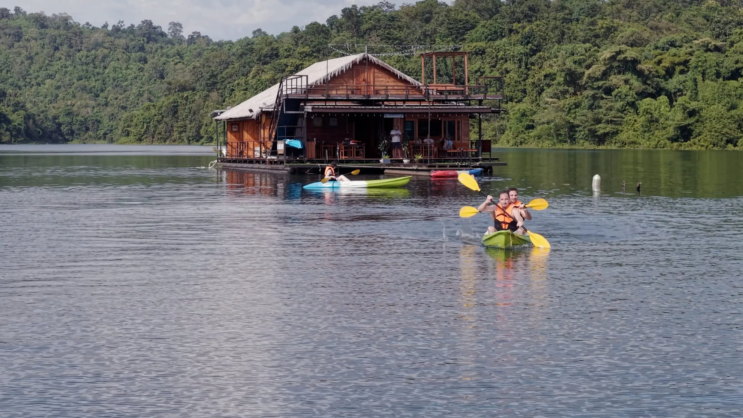 The floating house with a long-tail boat alongside on the misty morning lake.