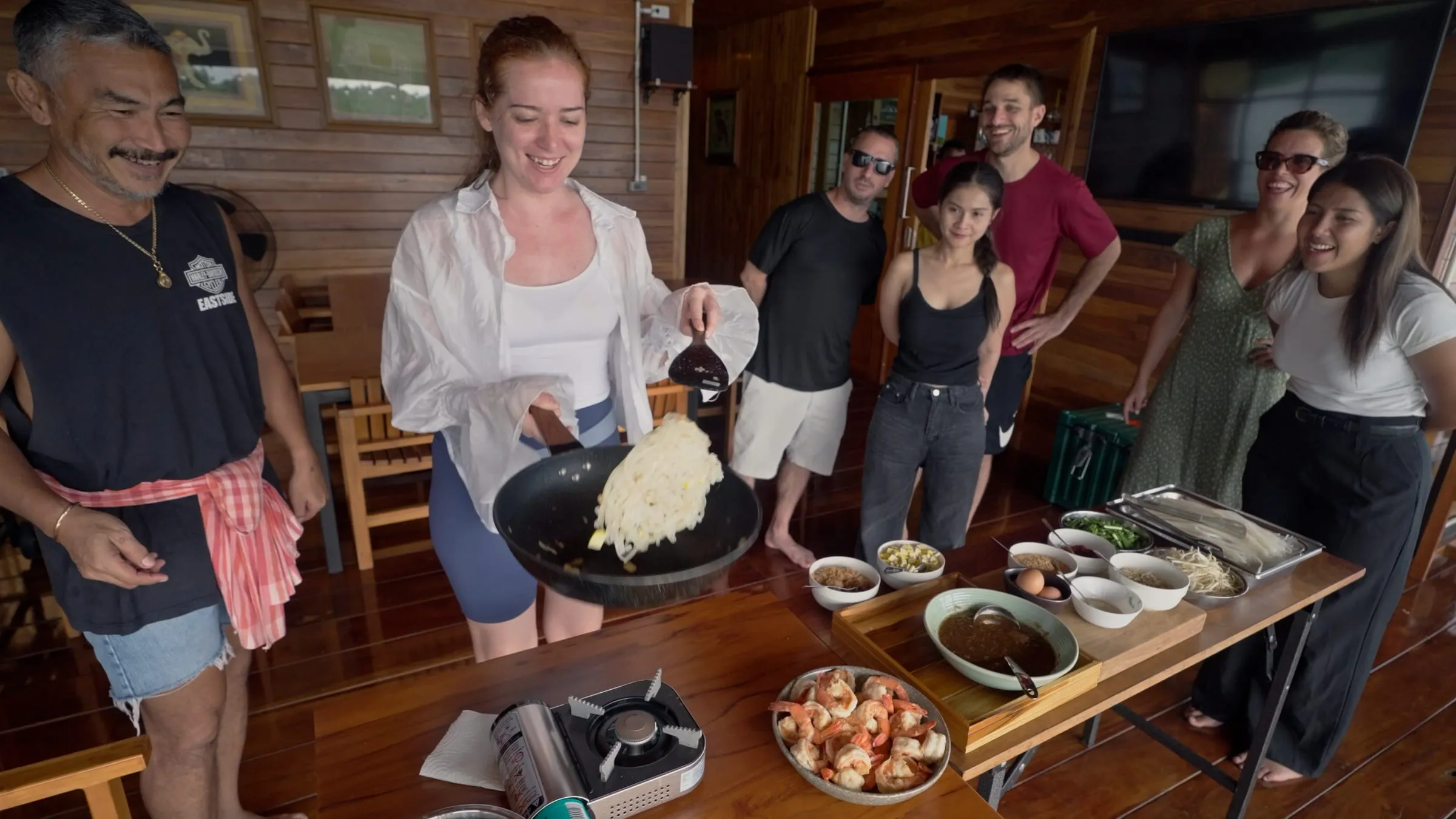 A group sharing a meal at the long table on the deck, the lake stretching out behind.